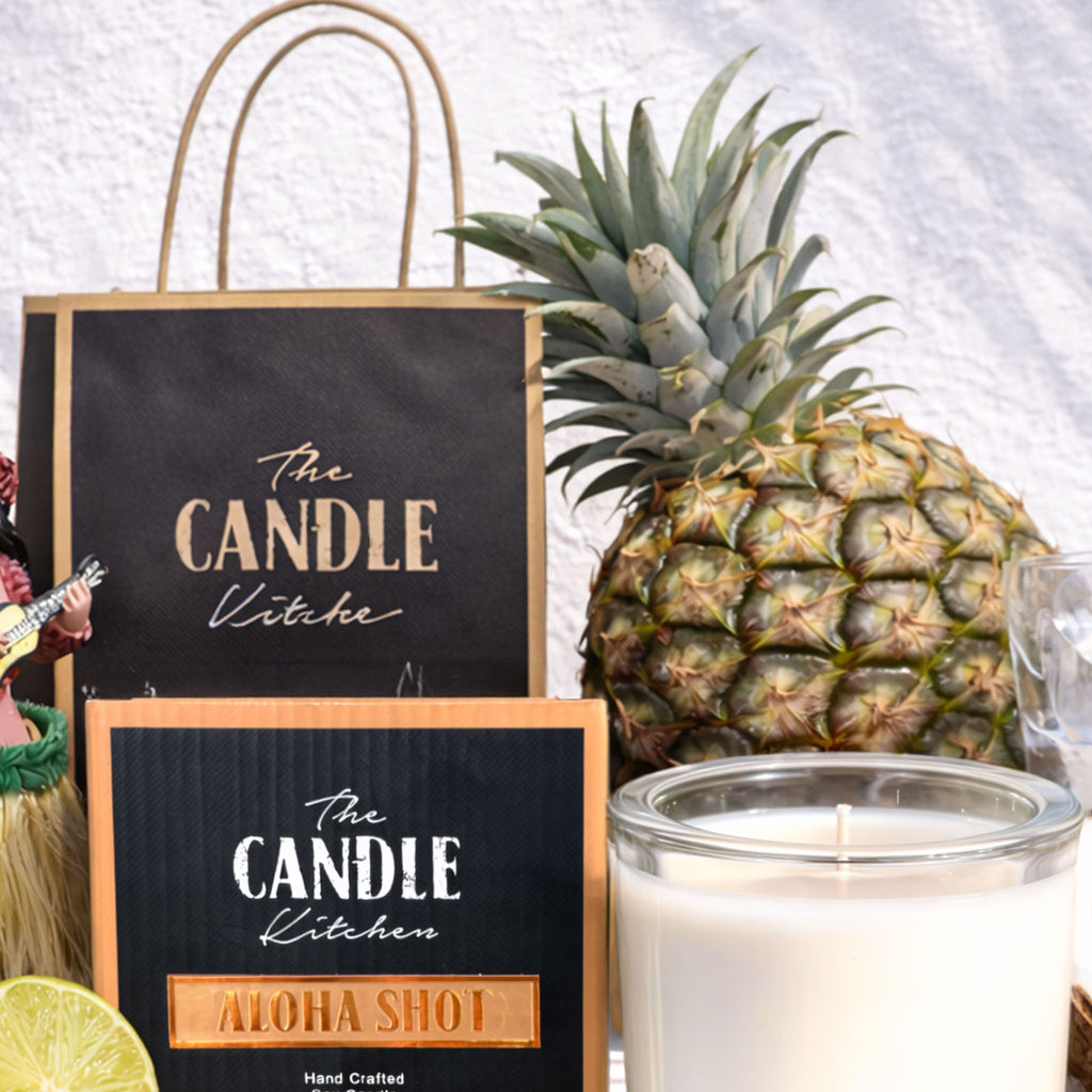 Aloha Shot Soy Candle the candle kitchen Candle with 'The Candle Kitchen' branding, pineapple, and gift bag on a white background