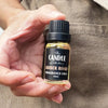 Amber Road fragrance oil The Candle kitchen, A hand holding a small glass fragrance jar with a black label .