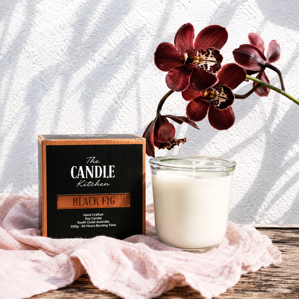 Black Fig Soy Candle The Candle kitchen, Candle with a flower and 'The Candle Kitchen' sign on a wooden surface
