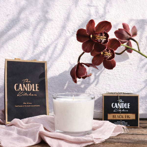 Black Fig Soy Candle The Candle kitchen, Candle with a flower and 'The Candle Kitchen' sign on a wooden surface