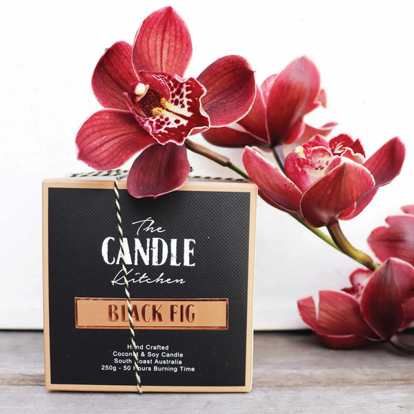 Black Fig Candle packaging with The Candle Kitchen branding and a Burgundy Orchid flowers in the background