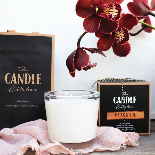 Candle from The Candle Kitchen with a box and red orchid flower on a white background