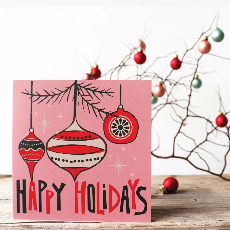 A Christmas card with a graphic of Santa Claus and the text 'HAVE A HOLY JOLLY CHRISTMAS' in red and white on a black background, displayed on a wooden surface with holiday decorations in the background.