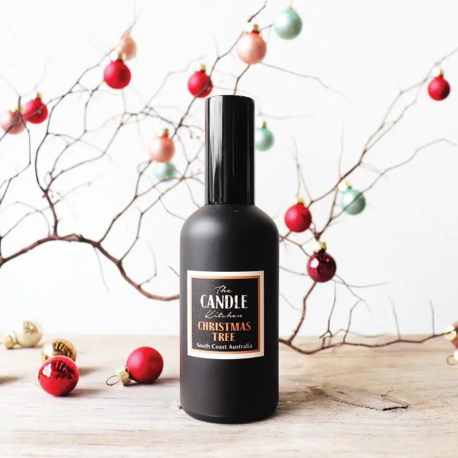 Black jar in front of tiny Christmas balls on a thin branch of wood.