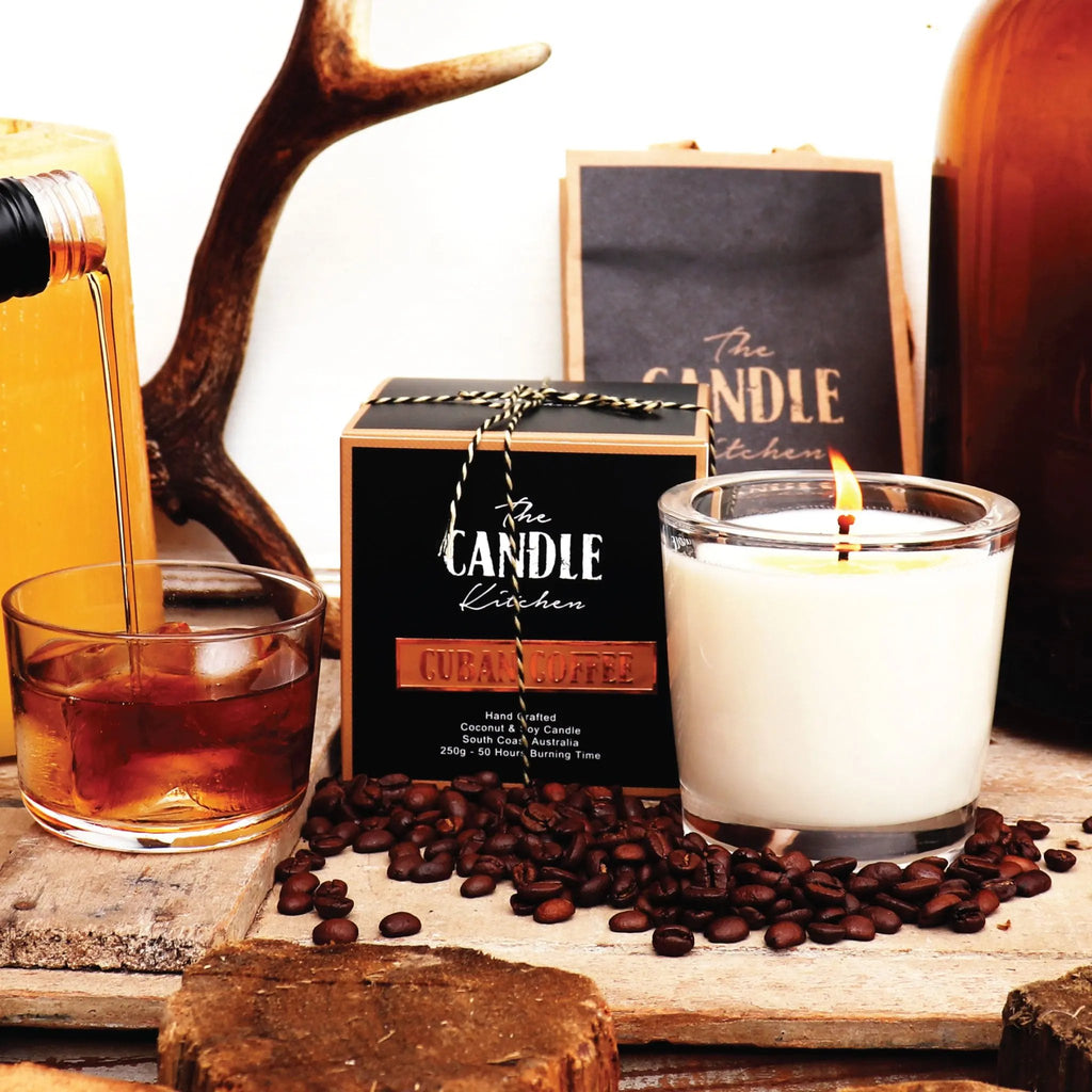 Candle with coffee beans and a glass of liquid on a wooden surface, featuring The Candle Kitchen branding. Coffee Creme Candle