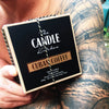 The Candle Kitchen box on the arm of a tattooed man. Coffee Creme Candle
