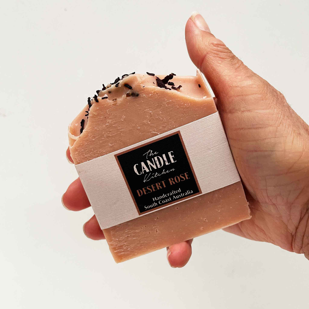 Hand holding a bar of soap with 'The Candie Kitchen' label on a light background