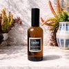 Escarpment room spray Candle Kitchen, Bottle of 'The Candle Kitchen Escarpment' on a textured surface with plants in the background
