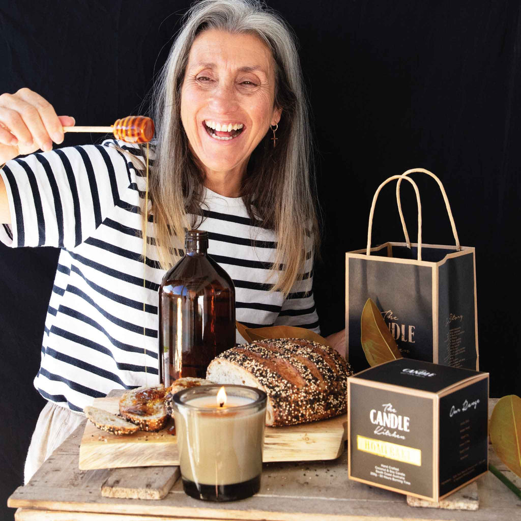 Petra having fun shooting the homebake candle. Standing in front of a black backdrop dribbling honey on bread with a candle burning in the forefront.