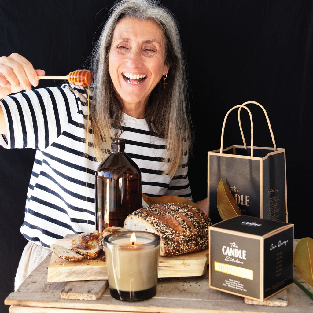 Petra having fun shooting the homebake candle. Standing in front of a black backdrop dribbling honey on bread with a candle burning in the forefront.