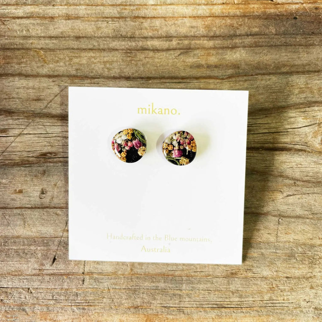 Floral stud earrings on a 'mikano' branded card against a wooden background
