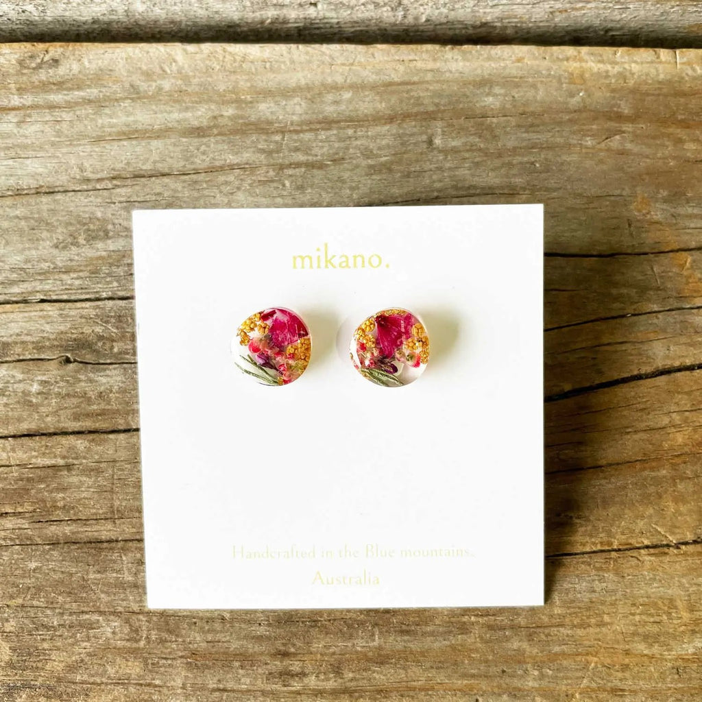 Floral earrings on a 'mikano' branded card against a wooden background