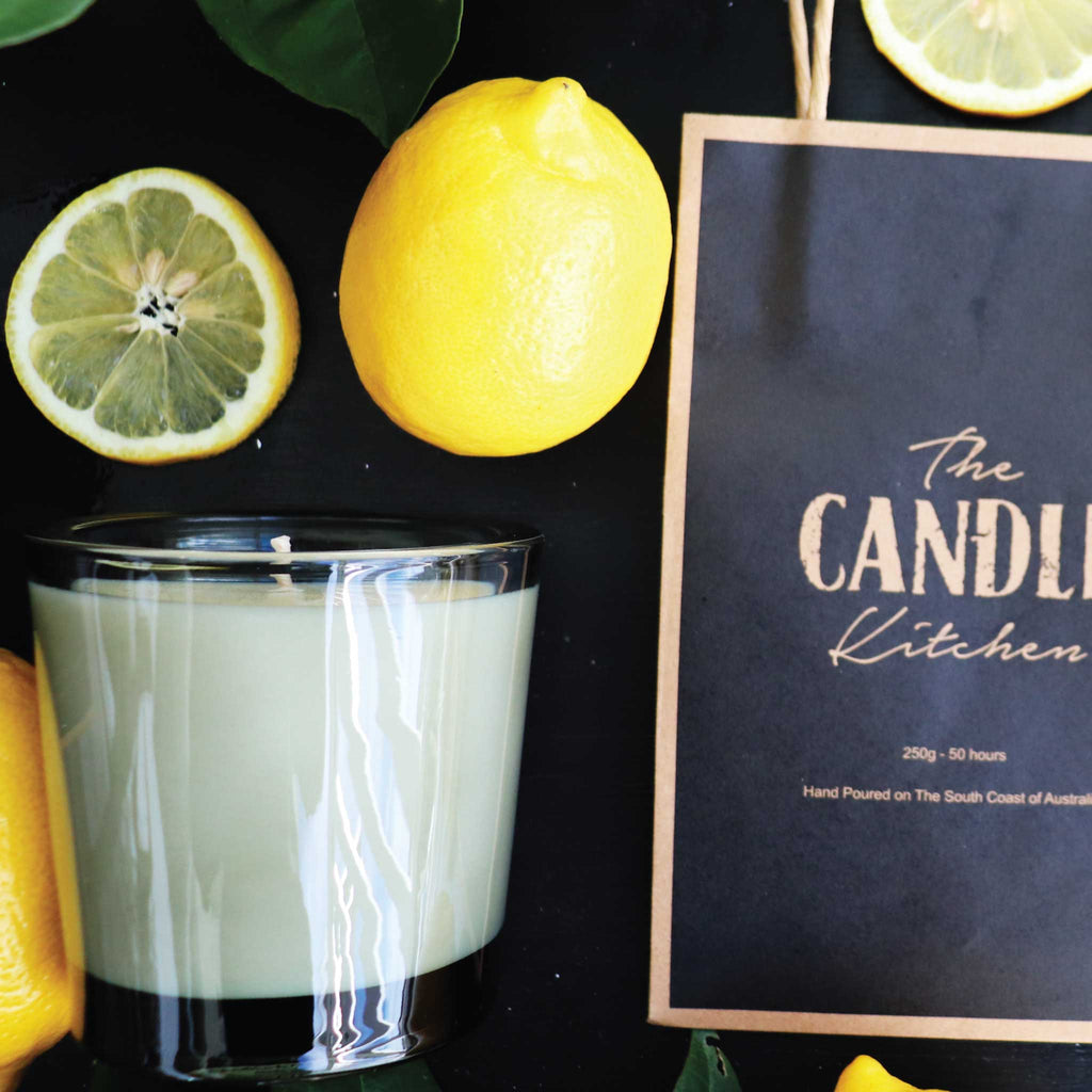 A Candle with lemons and 'The Candle Kitchen' bag on a dark surface.