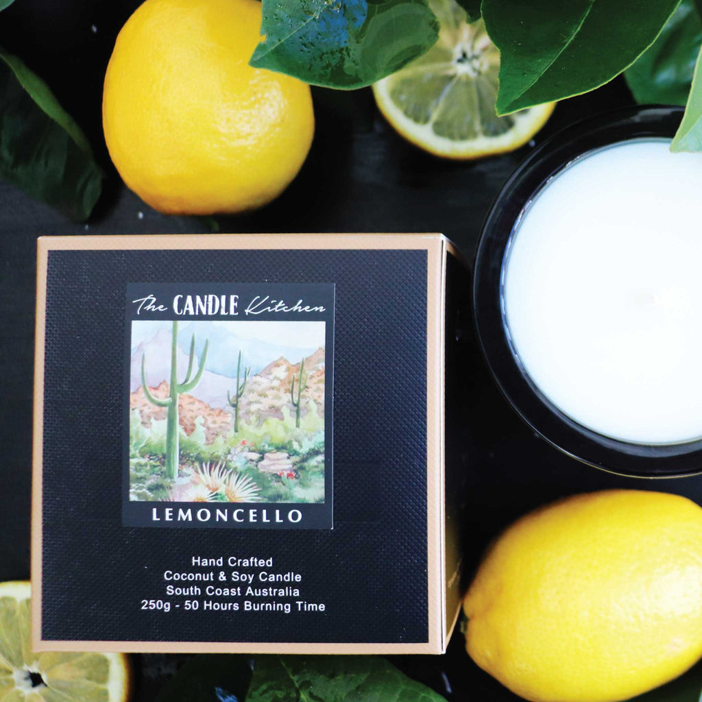 Lemoncello candle packaging with lemons and a candle on a dark table.