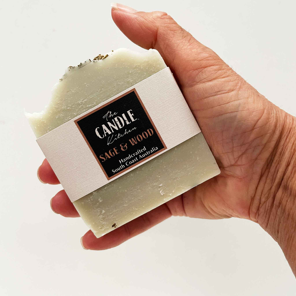 Hand holding a bar of soap with a visible label on a light background