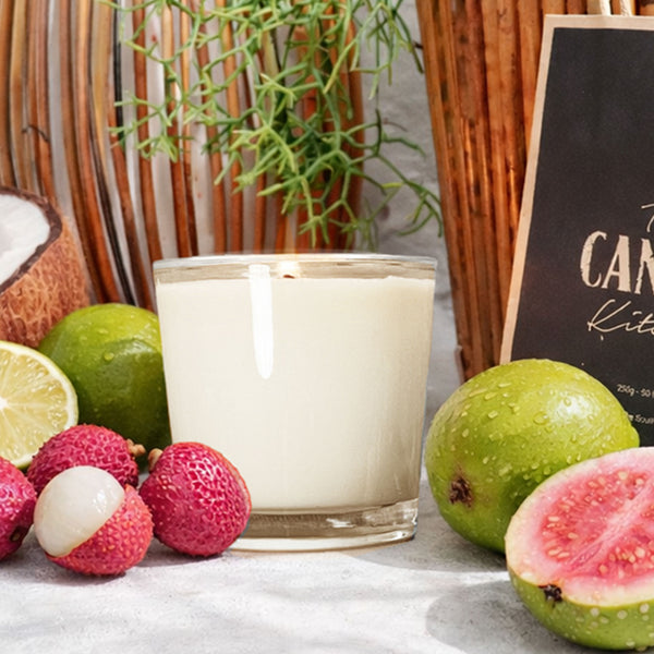 Tiki Island Soy Candle Kitchen, Candle with fruits and a plant on a textured surface