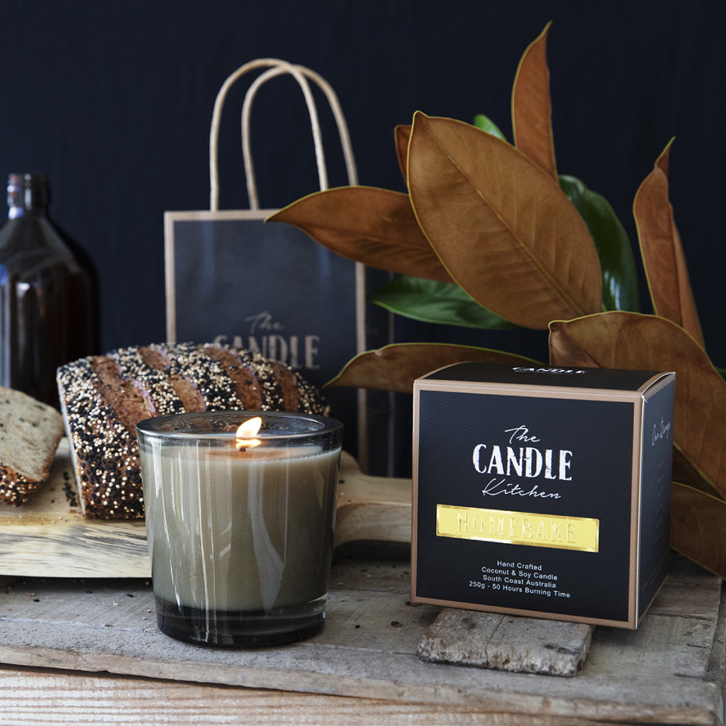 candle in a glass with bread and green leafs in background